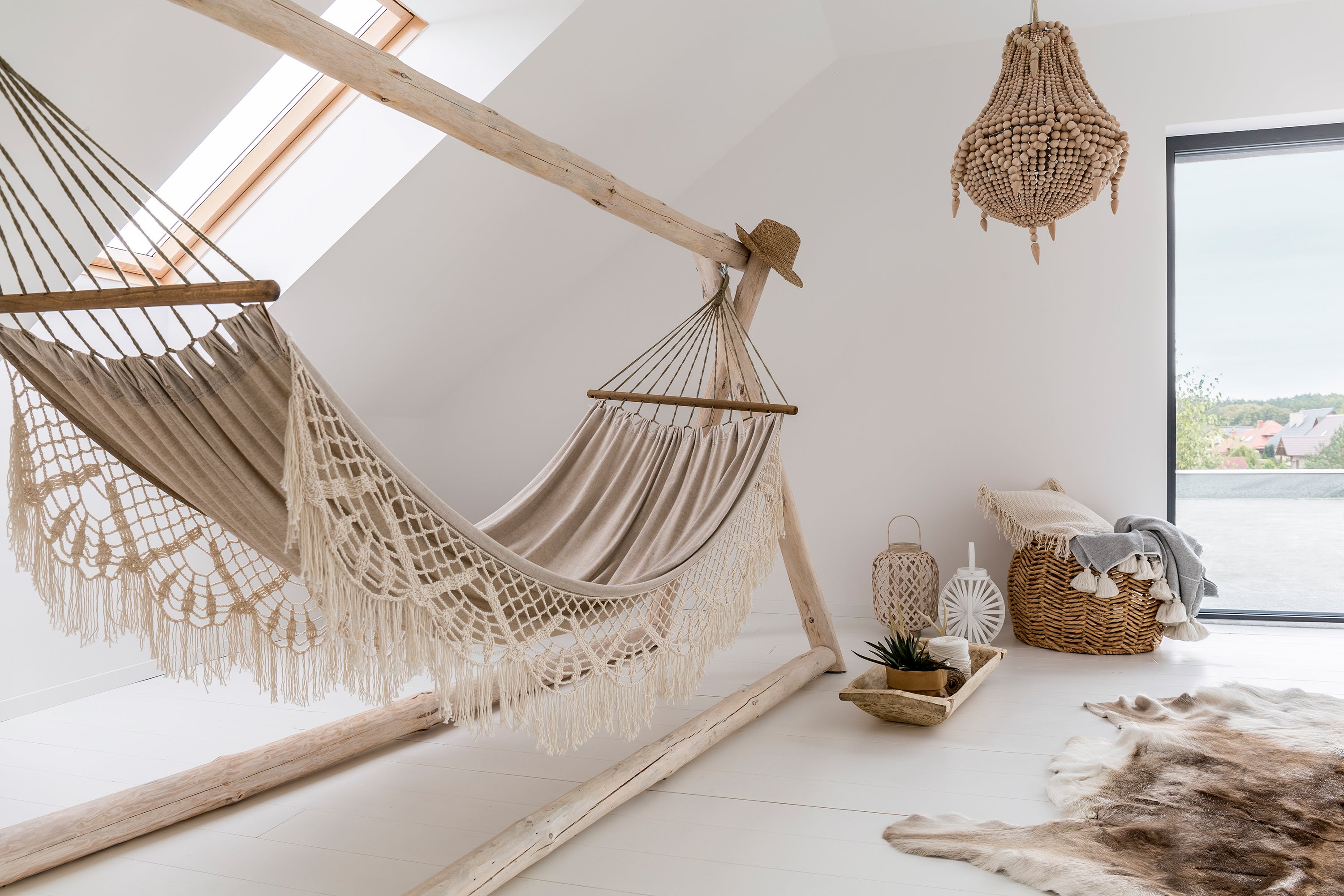 Helles Boho Interior Zimmer mit Hängematte mit Fransen, Fellteppich und weiteren Accessoires aus natürlichen Materialien wie Holz und Textil